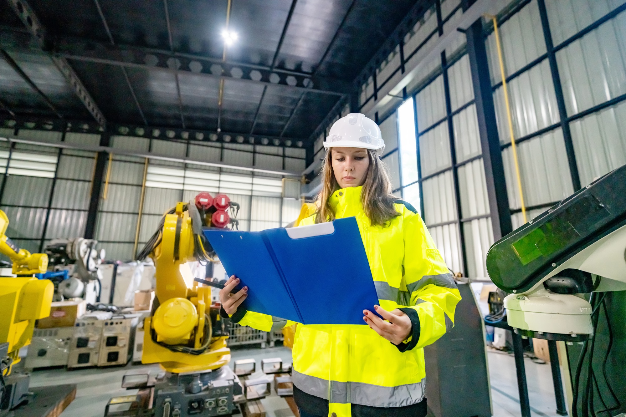 Worker Conducts Safety Inspection in Industrial Facility With Robotic Machinery